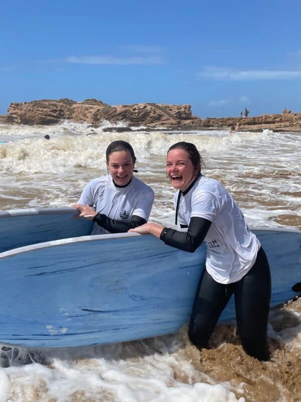 Two guests laughing in the water with a board