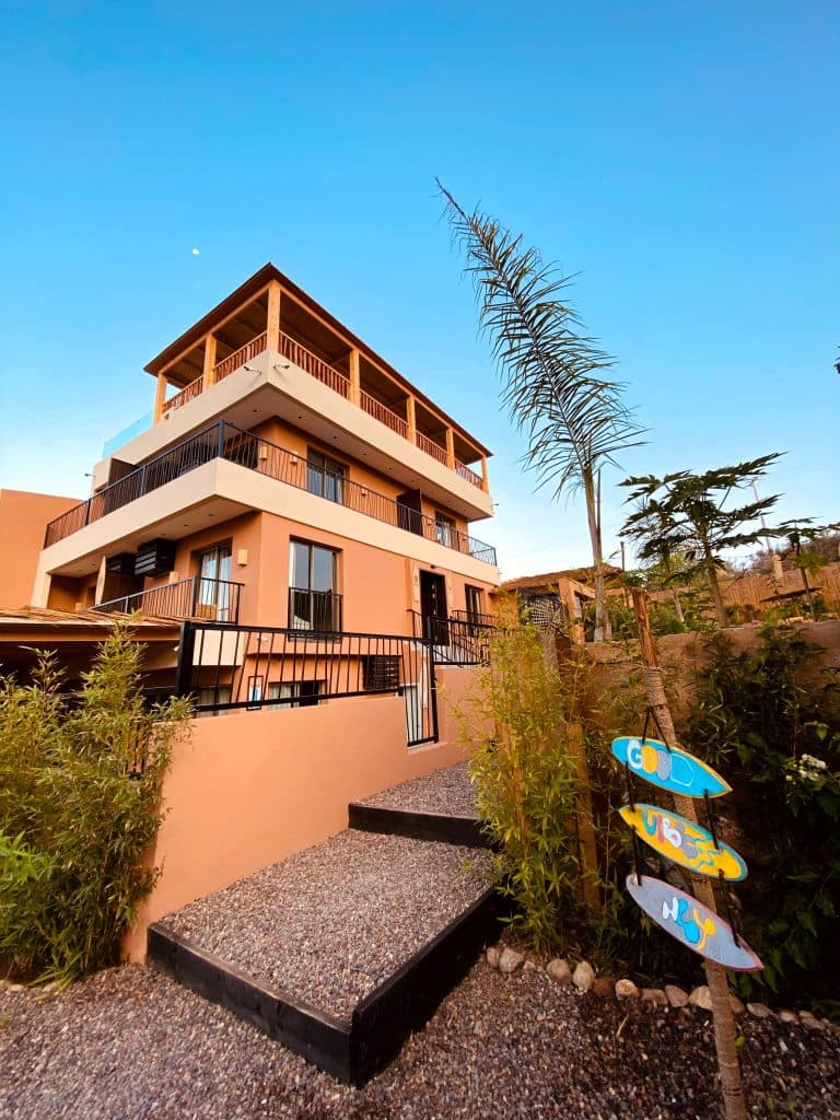The Harmony Surf Lodge building with palms and surfboards in the garden