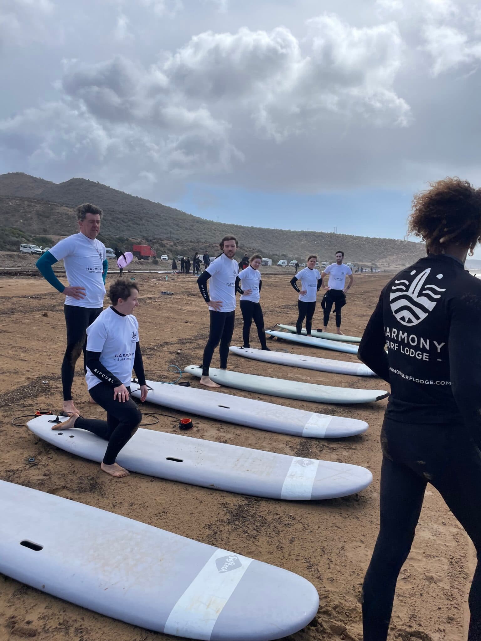 Vans loaded with surfboards parked above the beach