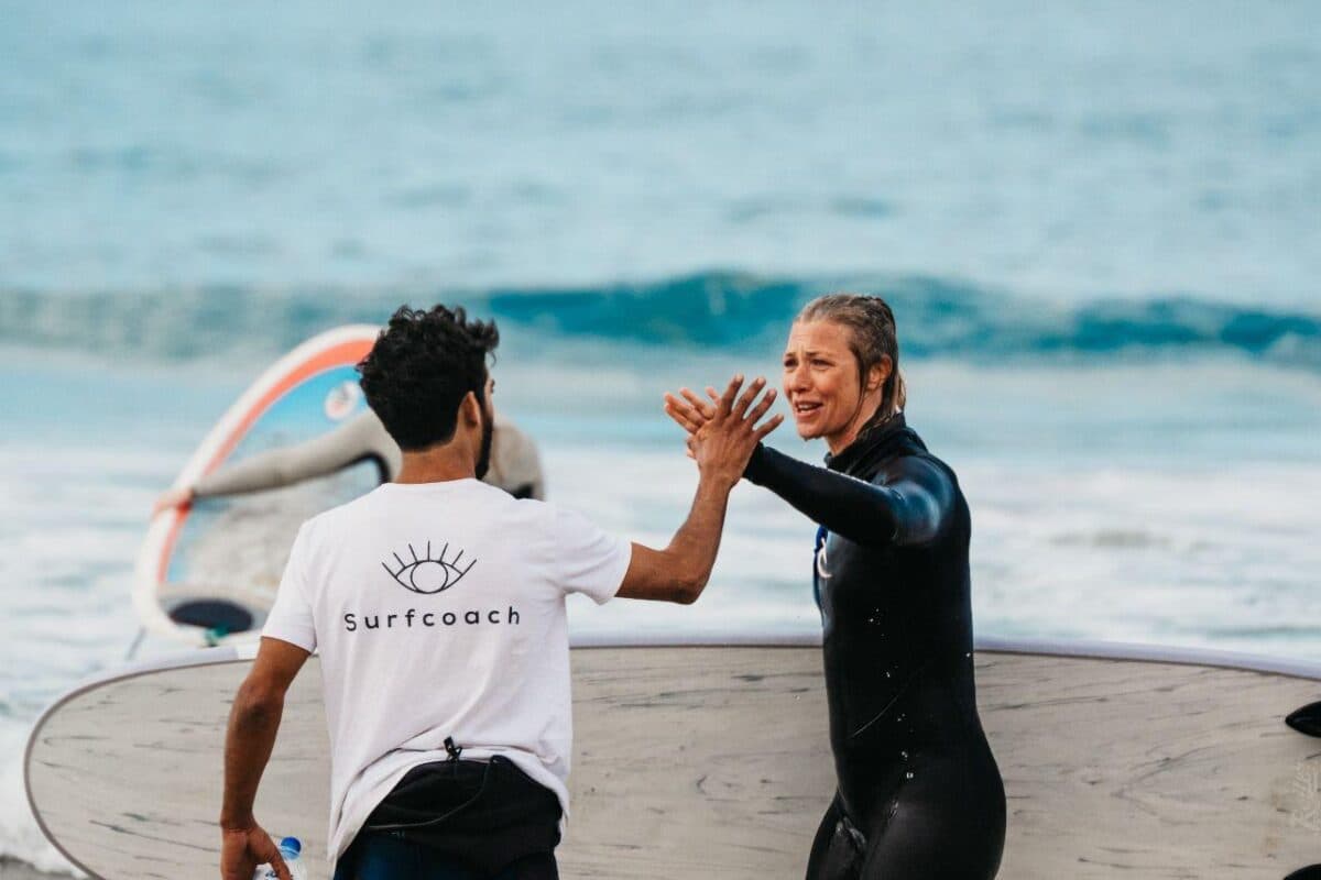 Two guests laughing in the water with a board